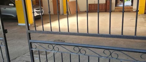 Un estacionamiento cerrado con suelo de hormigón y un edificio amarillo y blanco al fondo.