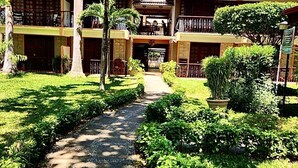 Un hotel con un patio central, varios balcones y abundante vegetación.