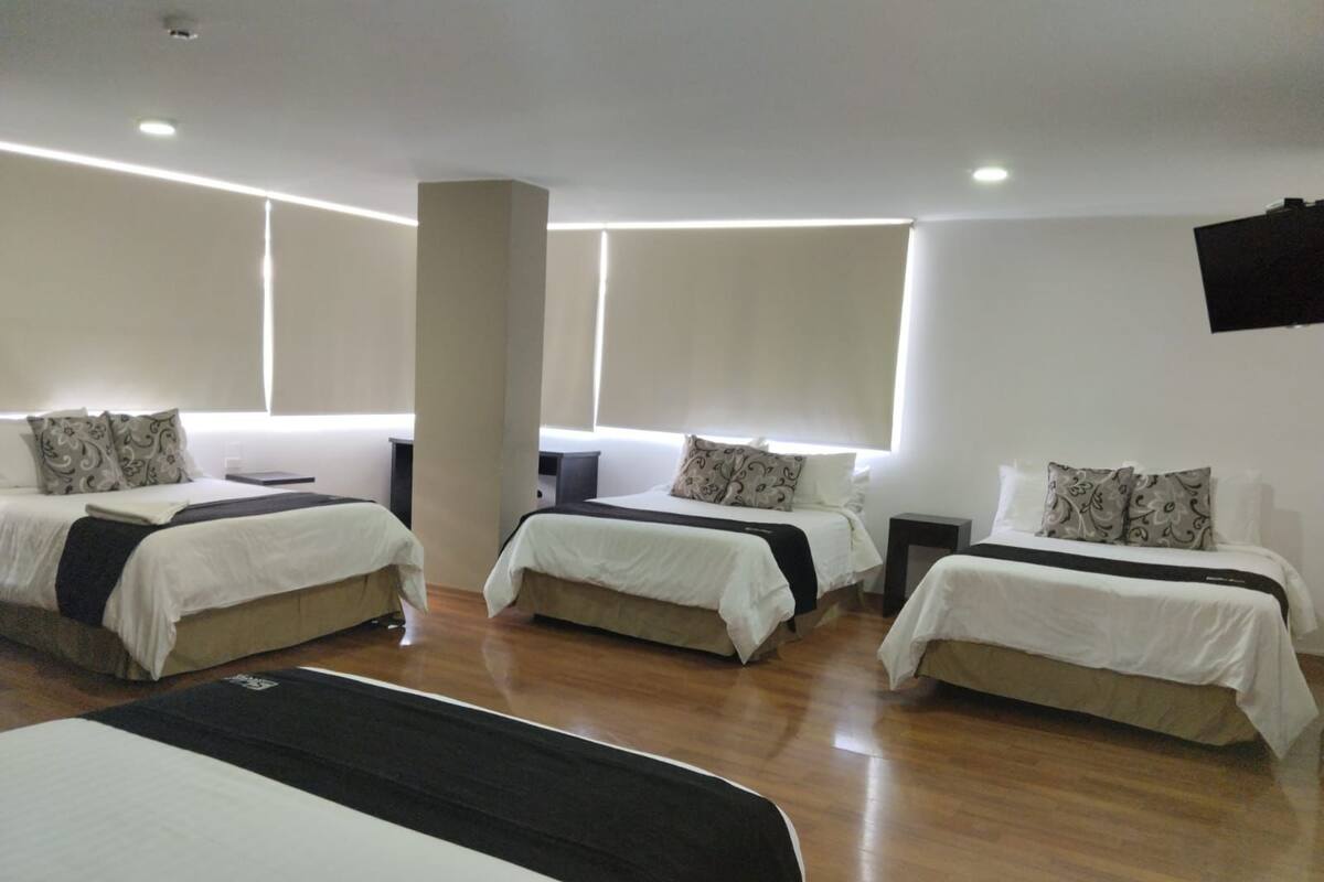 A hotel room with three single beds, a desk, and a chair.