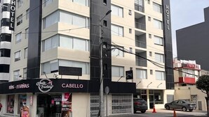 Un edificio de varios pisos con un letrero 'Sabot', indicaciones de 'Hotel' y una tienda 'Cabello' a nivel de calle.