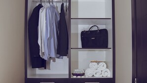 Un vestidor con ropa colgada, estantes para bolsos y zapatos, y cajones.