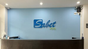 Una recepción con una pared azul y un letrero que dice 'Sabet Hotel'.