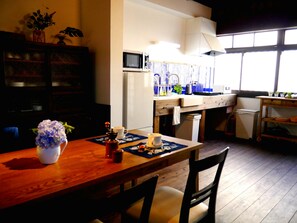 Une cuisine avec une table en bois, des chaises, un four à micro-ondes, un évier et une fenêtre.