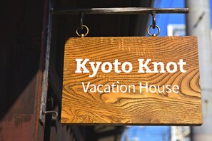 Une pancarte en bois portant l’inscription « Kyoto Knot Vacation House ».