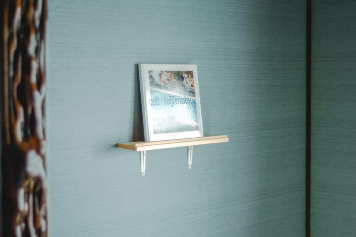 Un tableau encadré, posé sur une étagère fixée au mur.