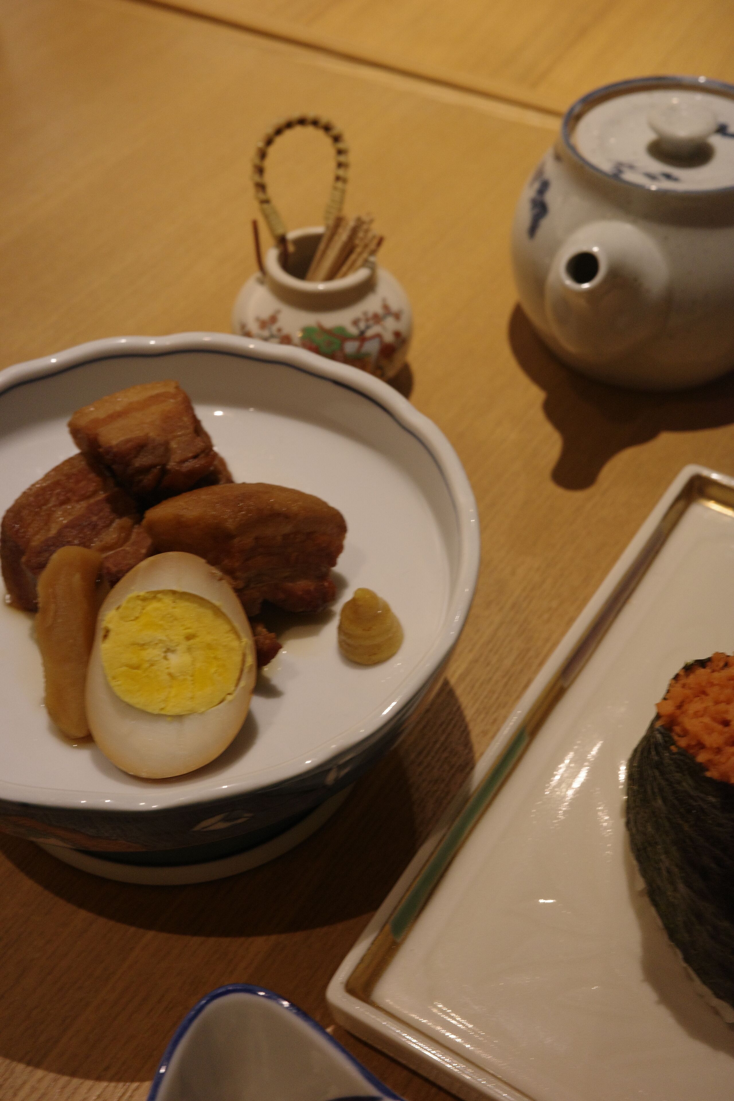 A dining table with a bowl of food, a teapot, and a small decorative item.