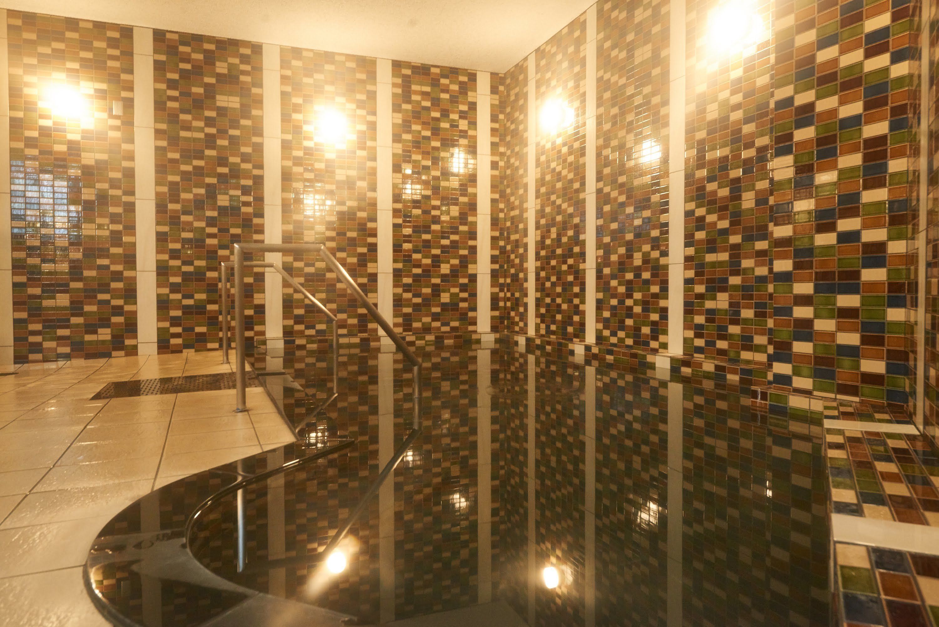 A modern bathroom with a checkered tile wall, a black bathtub, and a tiled floor.