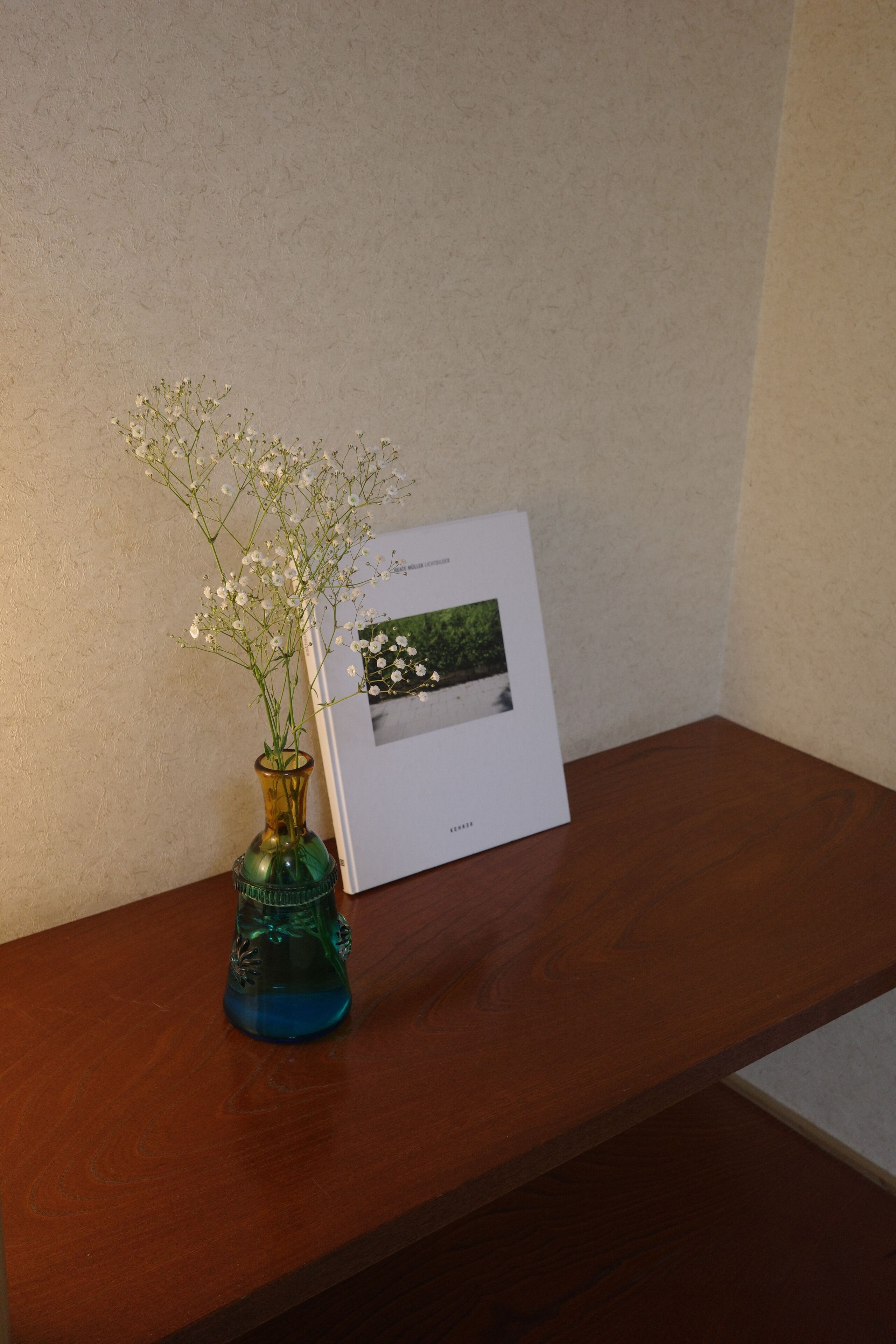 Een houten tafel met een vaas witte bloemen en een ingelijste foto.