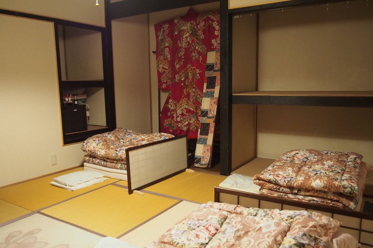 A traditional Japanese room with tatami flooring, two low bunk beds, a futon, and a shoji screen.