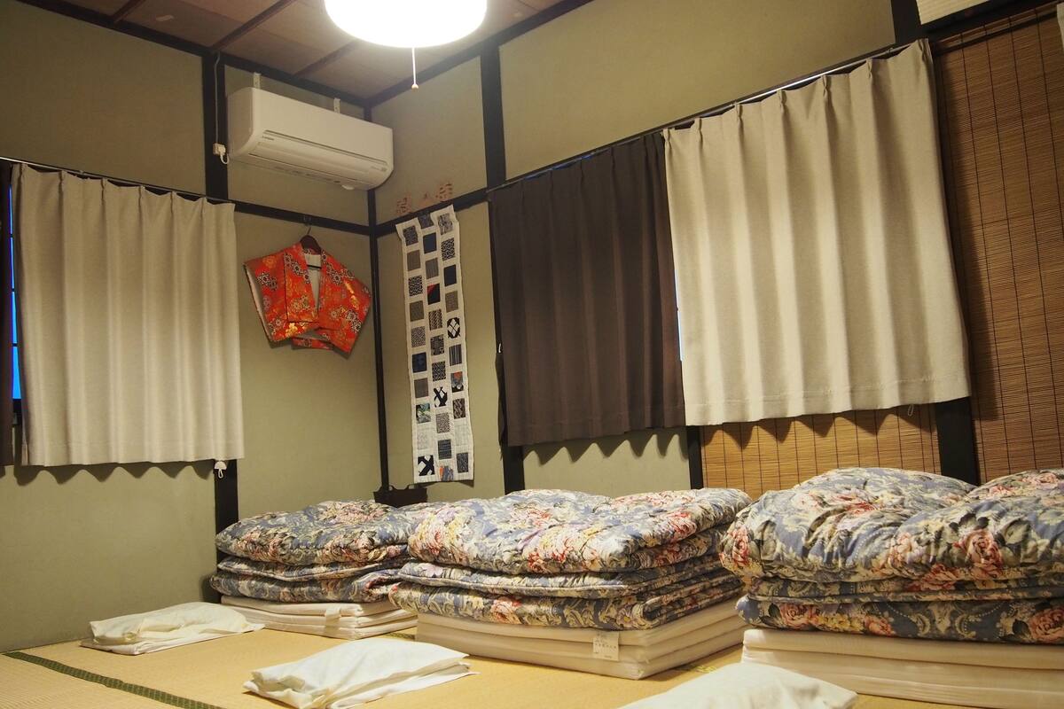 A traditional Japanese room with tatami mats, a futon bed, and a shoji screen.