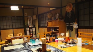 A traditional Japanese room with tatami mats, a wooden table with various items, and a bookshelf with books and decorative objects. - Kakure-Yado Yuji-inn - Hostel (Kurashiki)