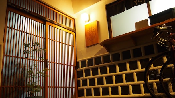 A traditional Japanese room with a sliding door, a bicycle, and a shelf with storage boxes. - Kakure-Yado Yuji-inn - Hostel (Kurashiki)