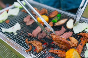 A grill with various meats and vegetables being cooked.