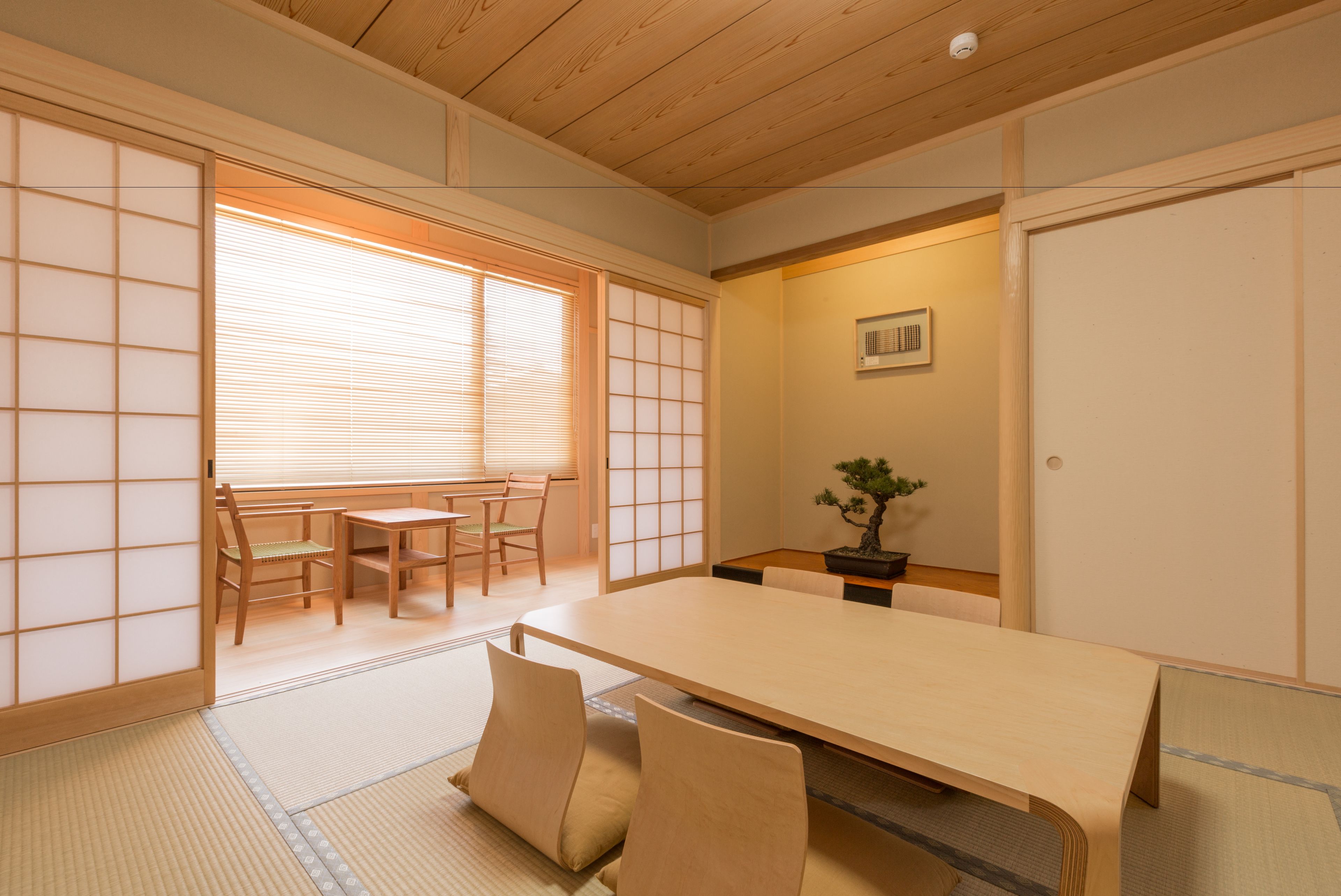 Ett traditionellt japanskt rum med tatamimattor på golvet, ett lågt bord och skjutdörrar.