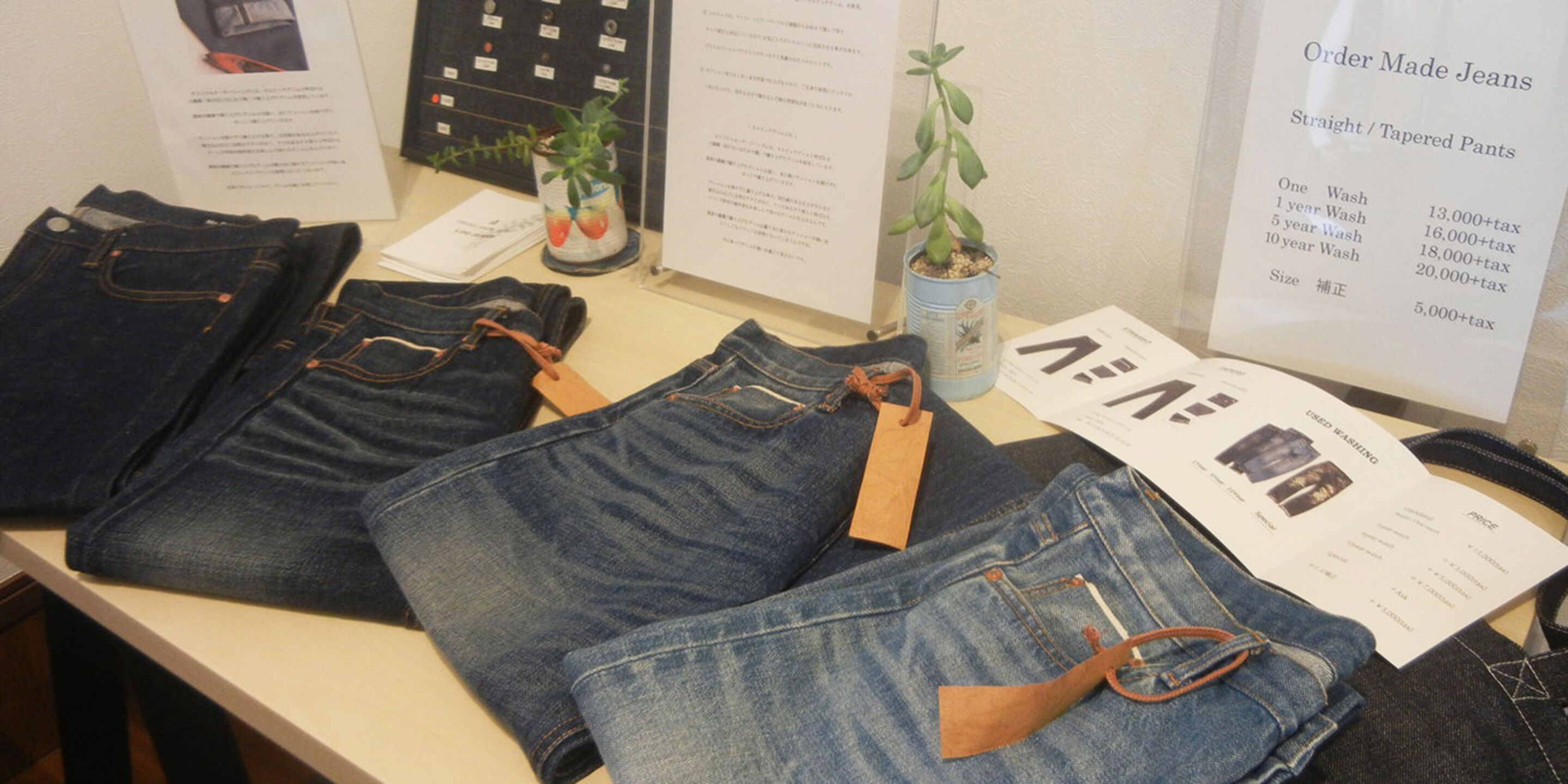 Exhibición de jeans con etiquetas de precio y un menú para ordenar jeans a medida.