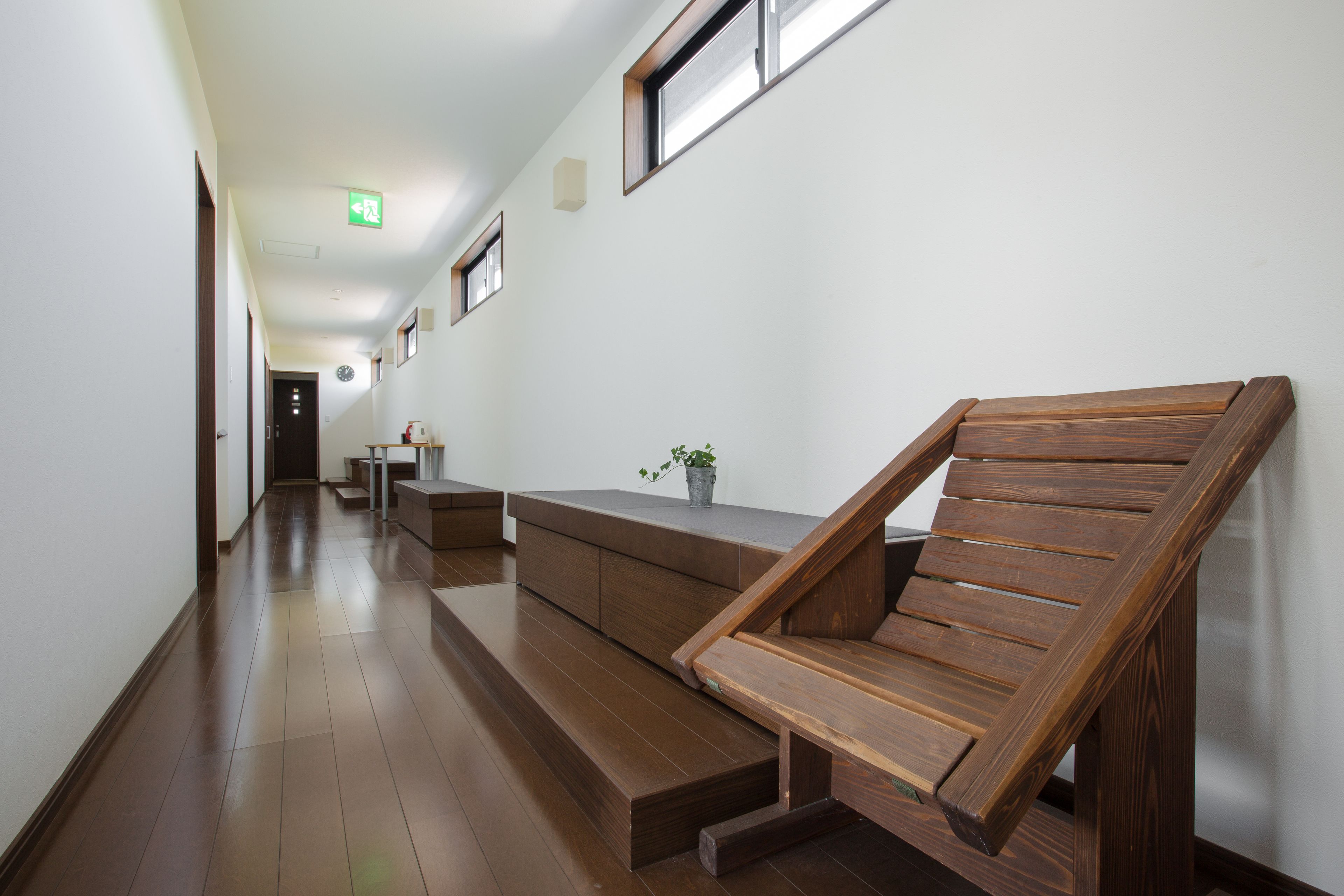 A hallway with a wooden bench, a small table with a plant, and a staircase leading to another room.