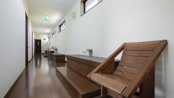 A hallway with a wooden bench, a small table with a plant, and a staircase leading to another room.