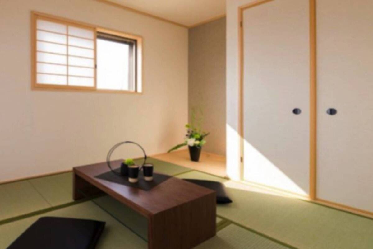 A traditional Japanese room with tatami flooring, a low wooden table with a tea set, a shoji screen window, and a door with a sliding mechanism.