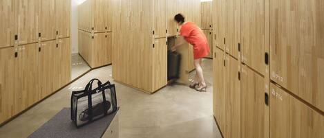 A hotel room with wooden lockers, a grey carpet, and a black bag on the floor.