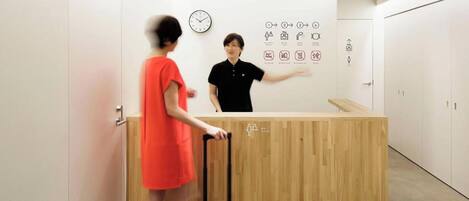 A reception desk with a wooden counter, a clock, and directional signs on the wall.