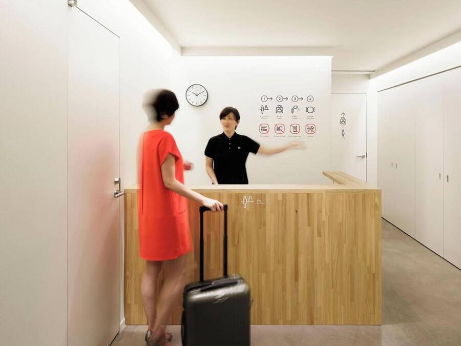 Un mostrador de recepción con encimera de madera, un reloj y carteles indicadores en la pared.
