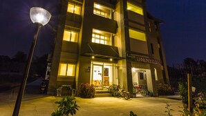 A multi-story building with a well-lit entrance, a bicycle parked outside, and a street lamp in the foreground. - backpackers.INN (Jinning)