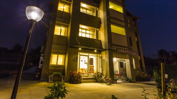 A multi-story building with a well-lit entrance, a bicycle parked outside, and a street lamp in the foreground.