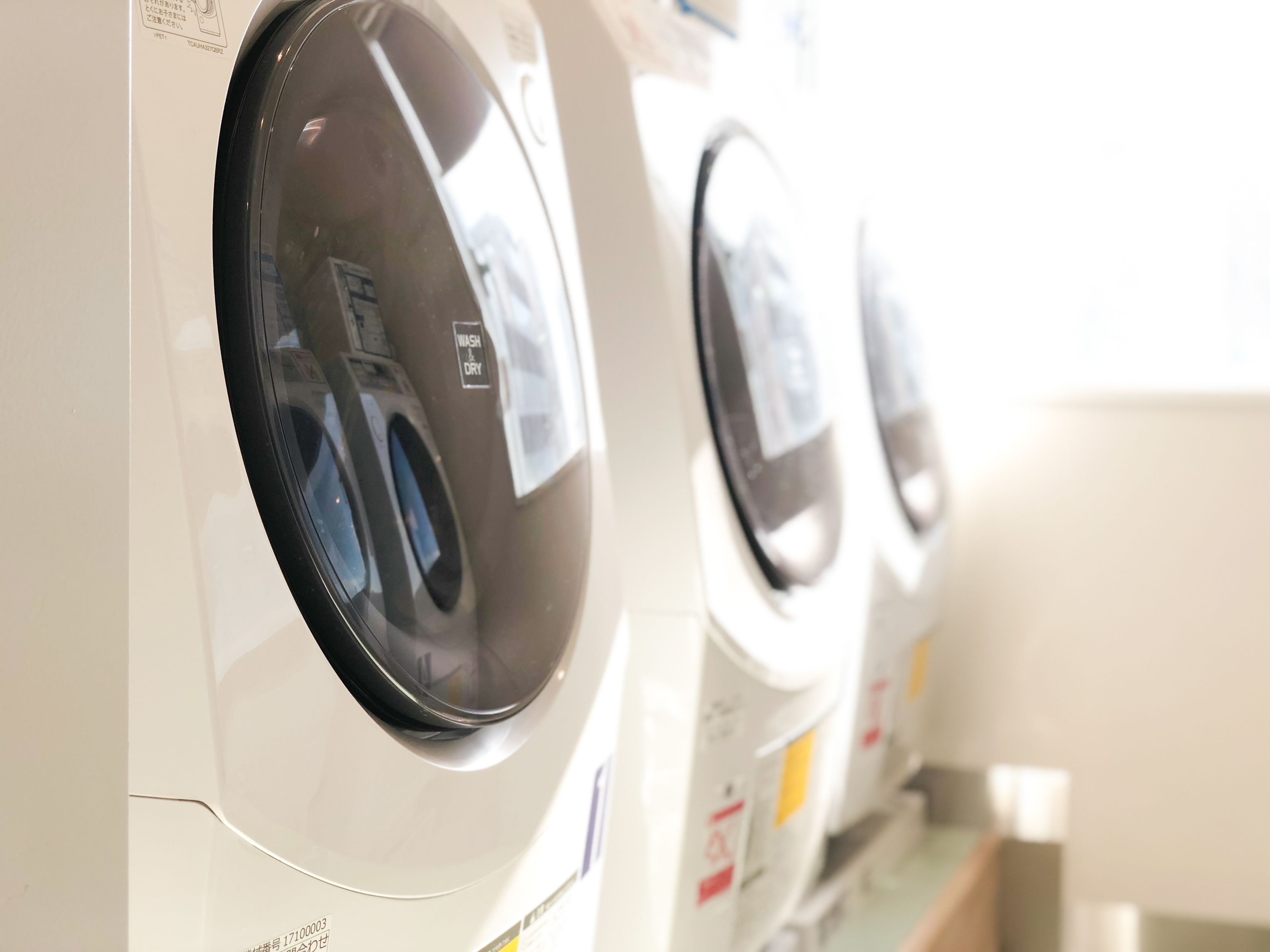 A row of front-loading washing machines in a commercial setting.