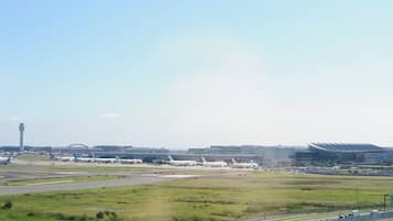 An airport with multiple airplanes parked on the tarmac, a control tower, and terminal buildings in the background.