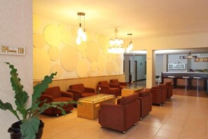 A lobby with seating, a reception desk, and a wall with circular patterns. - University Club Hotel UGM (Yogyakarta)