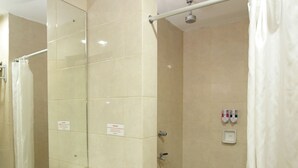 A bathroom with a sink, mirror, shower, and tiled floor. - University Club Hotel UGM (Yogyakarta)