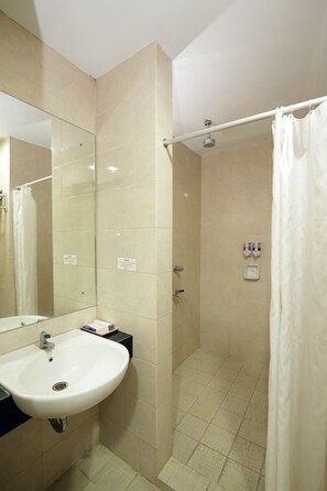 A bathroom with a sink, mirror, shower, and tiled floor. - University Club Hotel UGM (Yogyakarta)