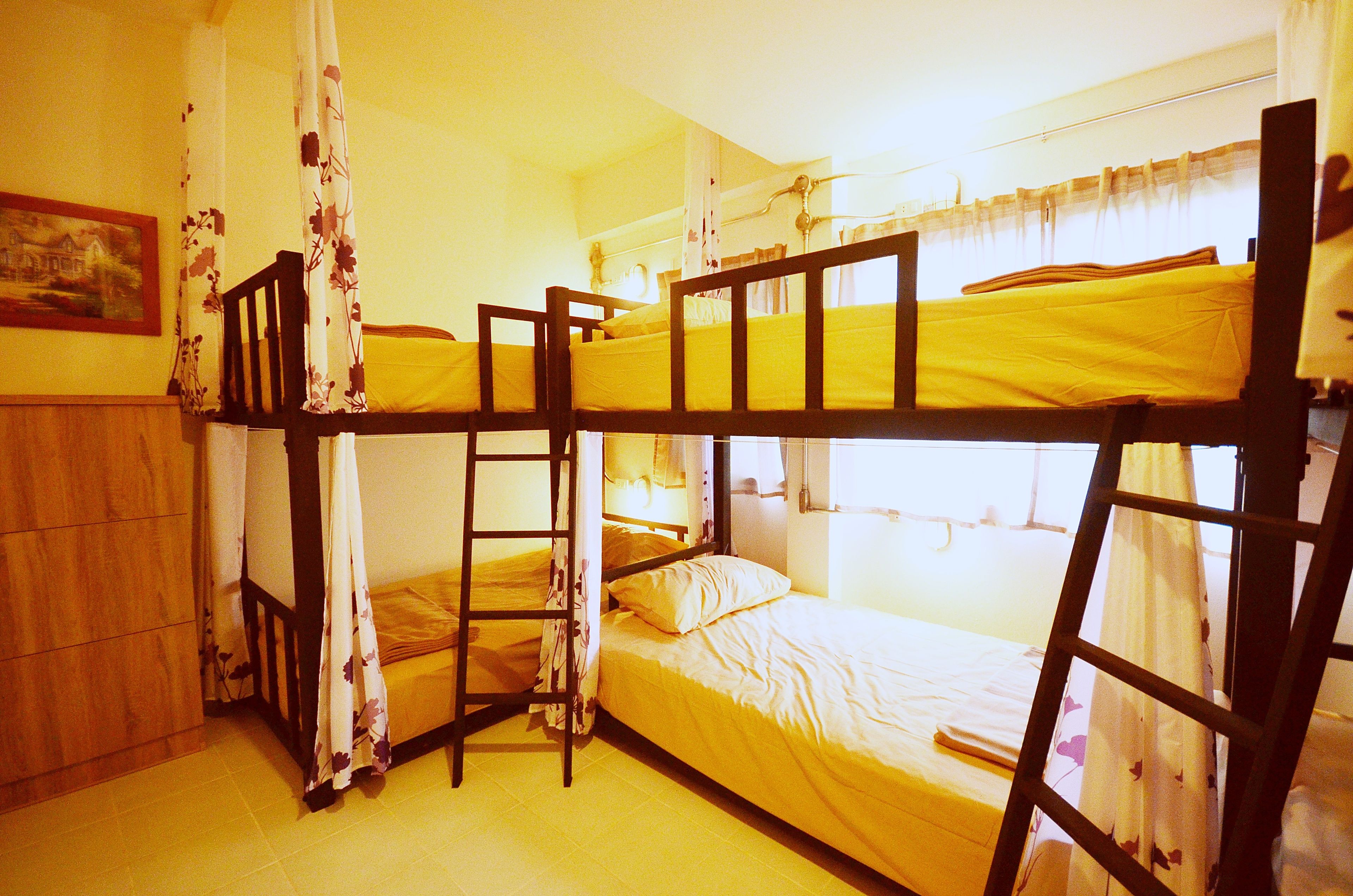 A bunk bed room with a ladder, a wooden wardrobe, and a painting on the wall.