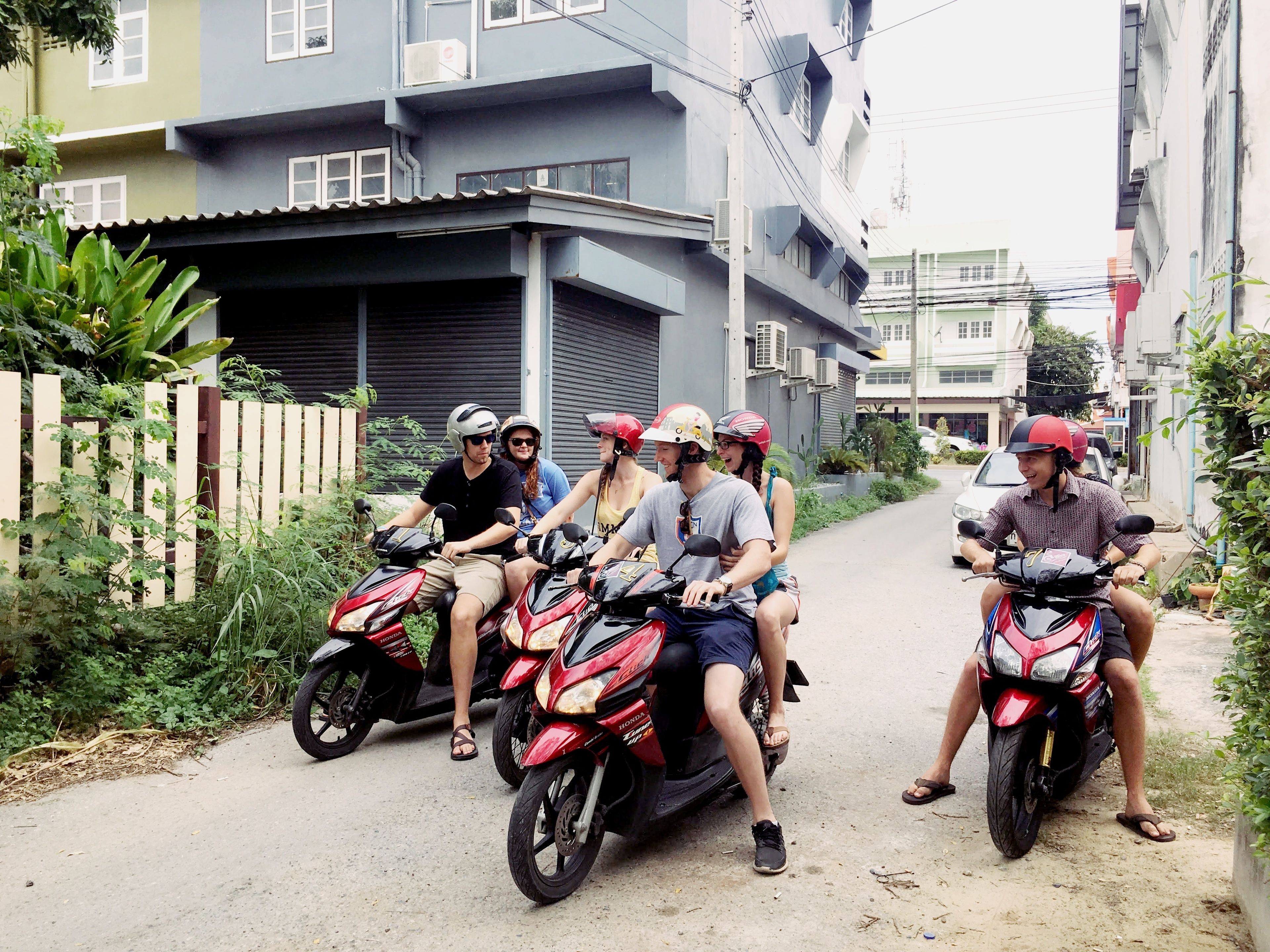 A group of people on motorcycles parked on a narrow street.