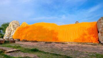 Un sitio histórico con antiguas estructuras de piedra y un muro grande cubierto de naranja.