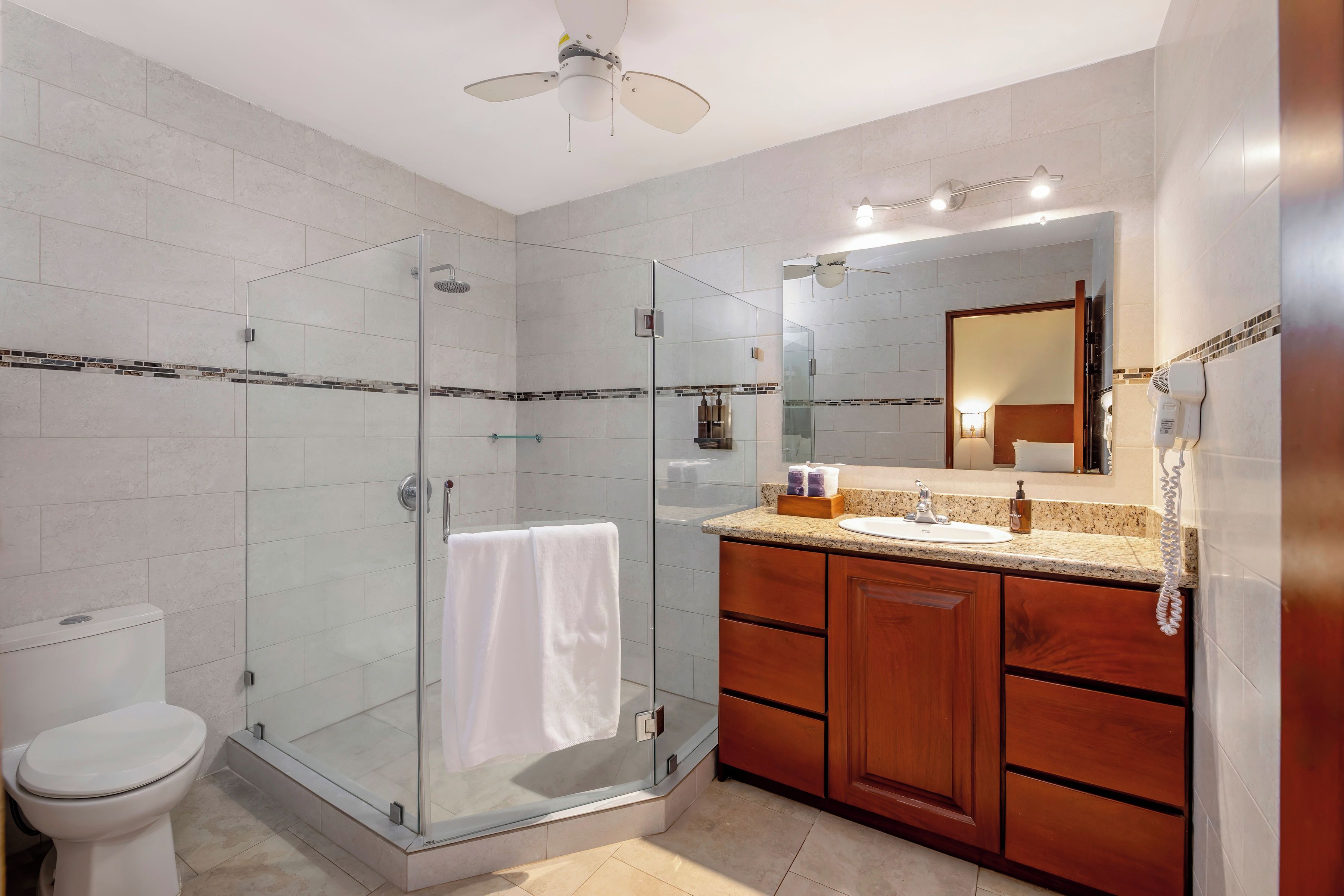 A modern bathroom with a glass-enclosed shower, a toilet, a sink with a vanity, and a mirror.