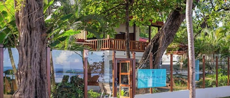 A coastal hotel with a wooden deck, large windows, and a sign reading "The Coast Hotel".