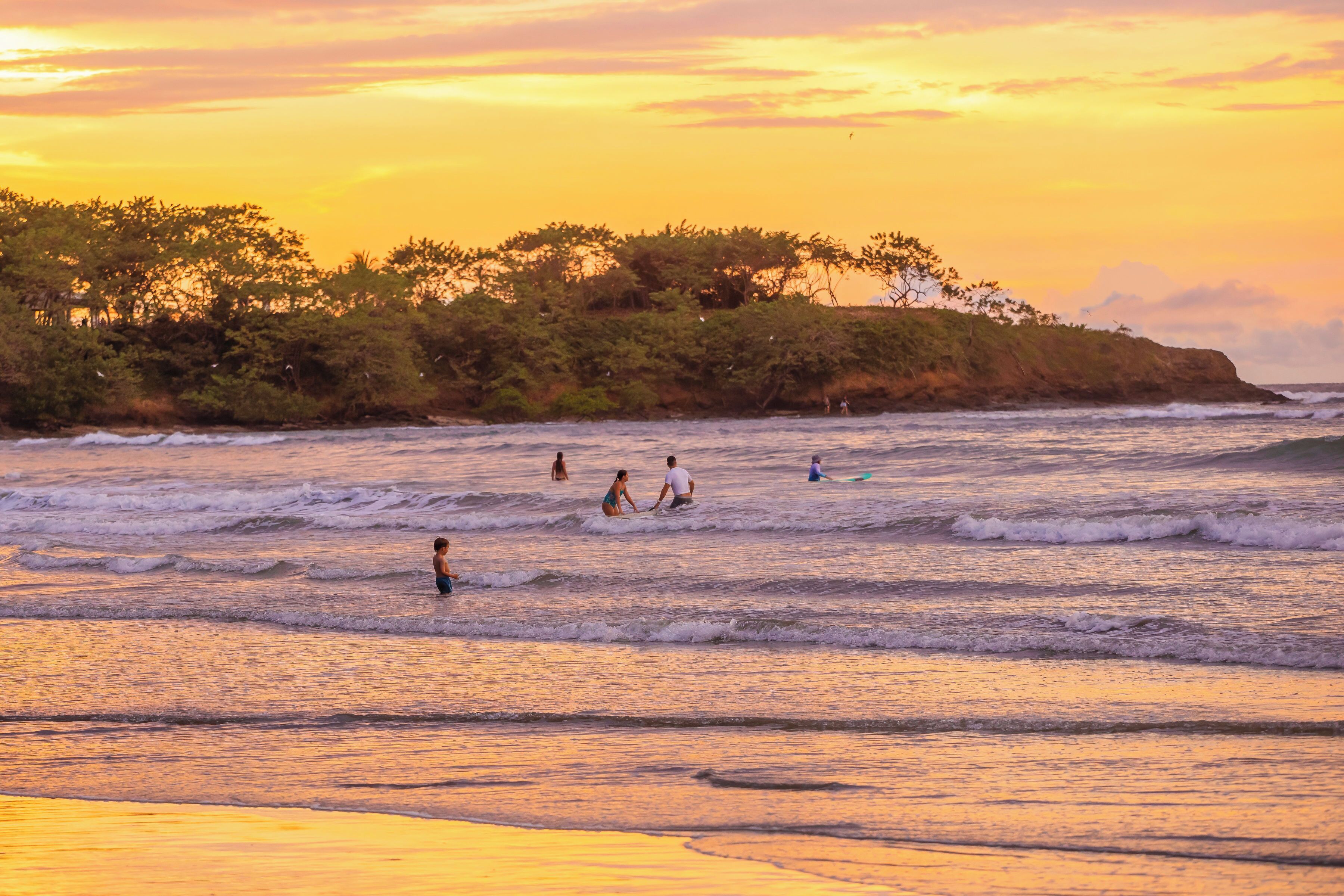 Une scène de plage avec des vagues et des personnes dans l’eau.
