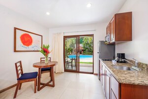 A compact kitchen with a dining area, a view of a swimming pool, and a ceiling light.