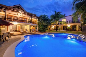 Una piscina al aire libre, sombrillas, sillones reclinables de piscina