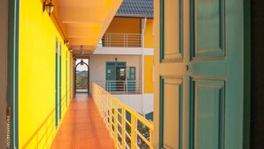 Un couloir avec un sol carrelé, une porte verte et des murs jaunes.