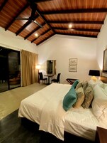 A bedroom with a large bed, a desk, and a chair. There is a ceiling fan and a sliding glass door leading to an outdoor area.