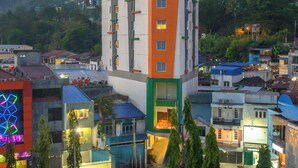 Un hôtel à plusieurs étages, doté d’une façade orange et blanche bien visible, entouré d’autres bâtiments et de verdure.