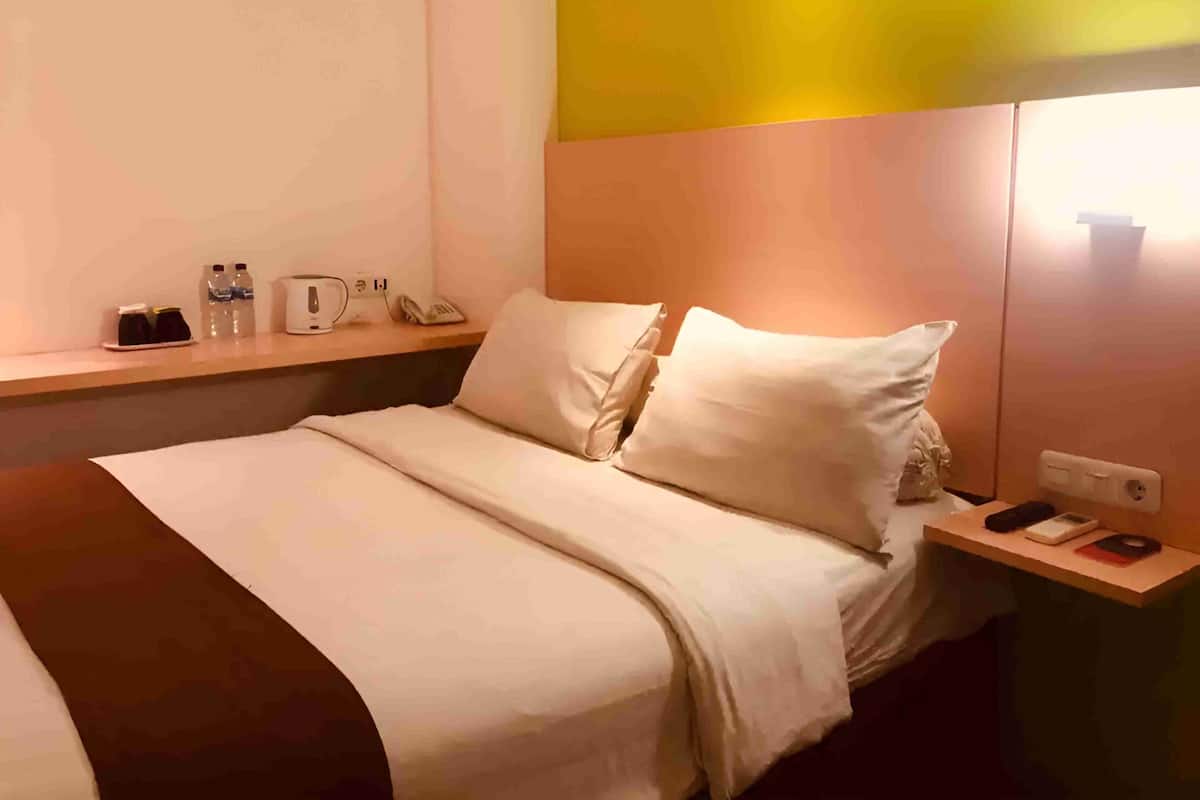 A hotel room with a bed, bedside table, and a nightstand.