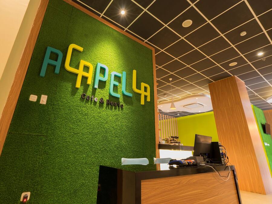 A reception area with a green wall and the name 'ACAPELLA' in large letters.
