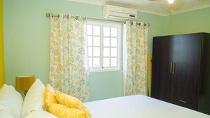 A bedroom with a bed, curtains, a wardrobe, and an air conditioning unit.