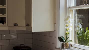 Cocina con alacenas blancas, una olla negra sobre la encimera, un lavamanos y una ventana con orquídeas blancas.