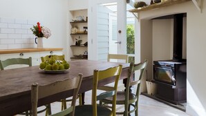 Een eetruimte met een houten tafel, stoelen, een dakraam en een open haard.