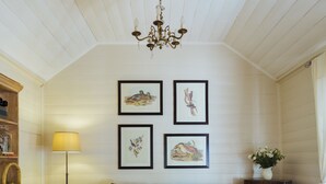 Een gezellige woonkamer met een donkergrijze bank, een houten salontafel en een tapijt met een patroon. Er staat een vloerlamp, een kast met decoratieve objecten en er hangt kunst op de muur.