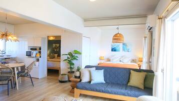 A modern, well-lit room with a sofa, dining table, and kitchen area.